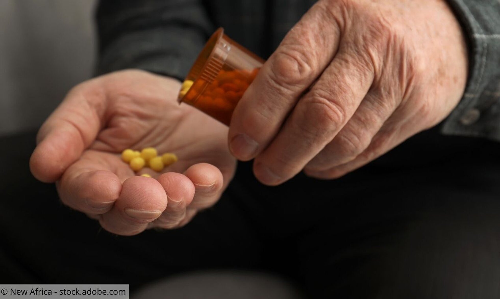 Nahaufnahme von Händen eines Seniors, der sich Tabletten in die Hand schüttet