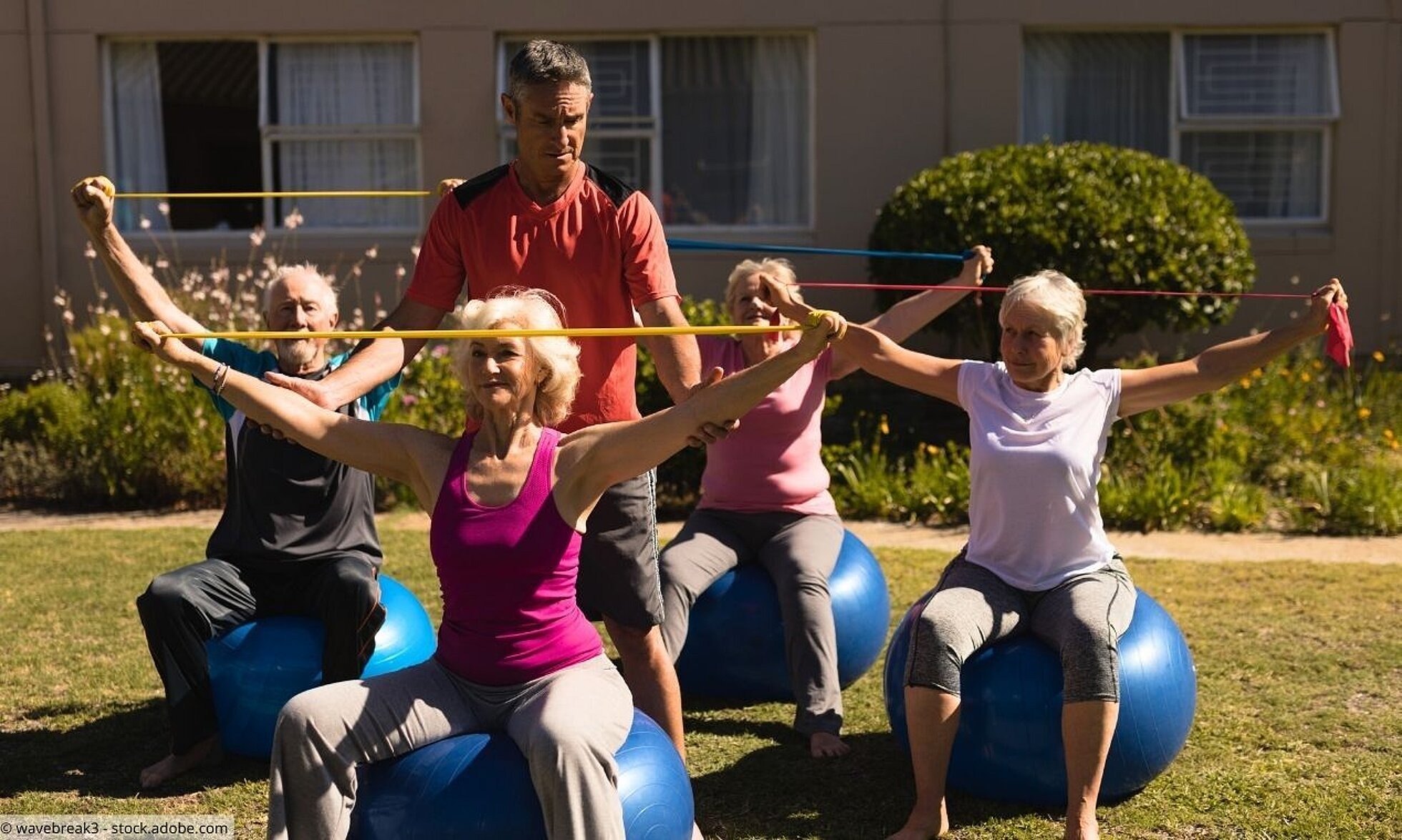 Seniorengruppe auf Gymnastikbällen mit Trainer bei Sportübungen