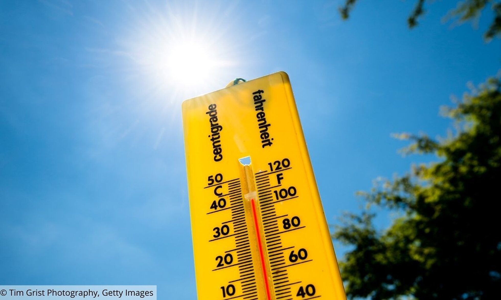 Hitzeschutz in Kommunen Gelbes Thermometer vor blauen Himmel und Sonnenschein