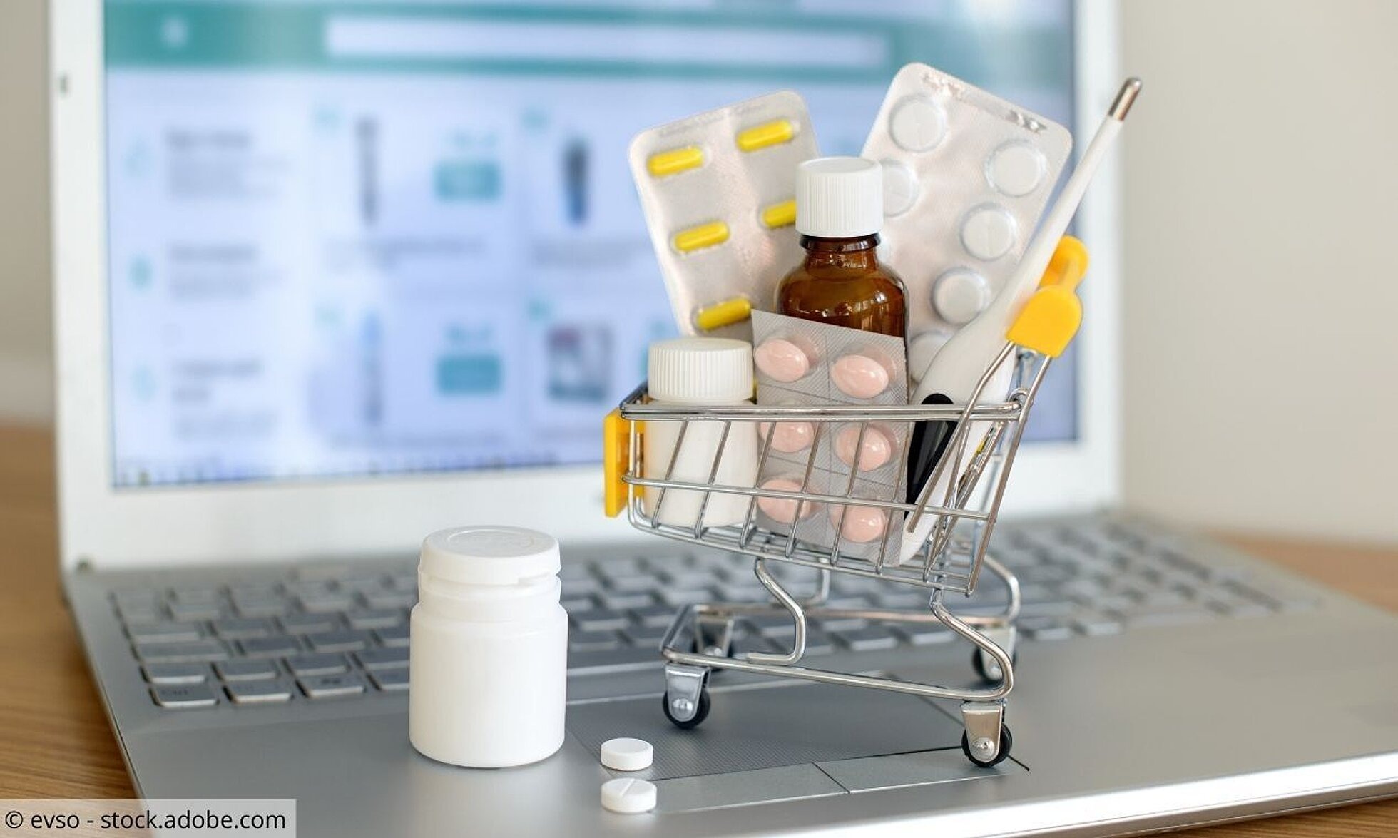 Kleiner Einkaufswagen mit Tabletten steht auf Laptop
