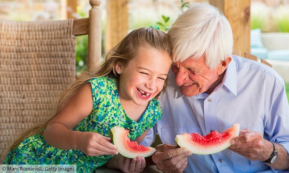 Gesund Essen im Alter Enkelin und Großvater essen Melone