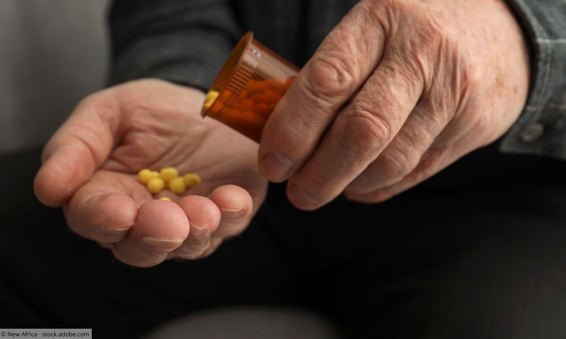 Nahaufnahme von Händen eines Seniors, der sich Tabletten in die Hand schüttet