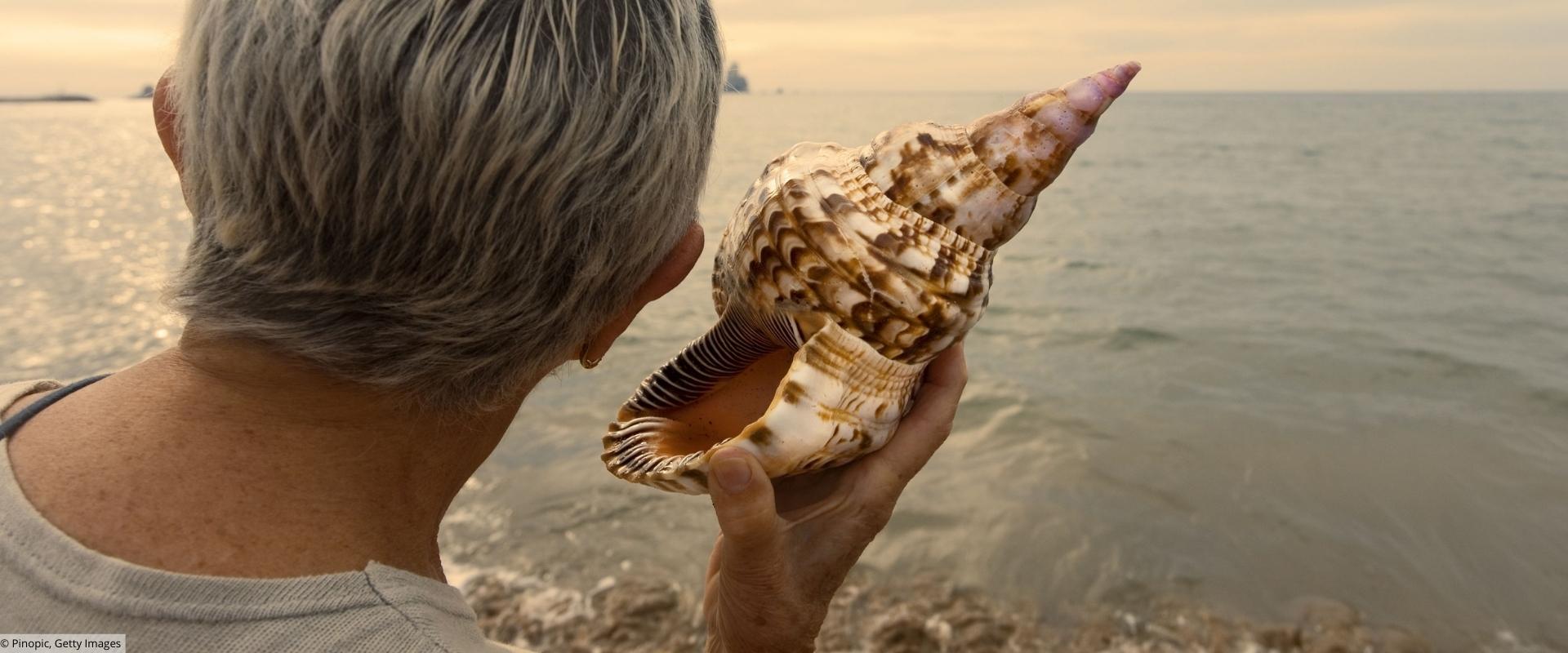 Hörgesundheit im Alter Ältere Frau hört an großer Muschel