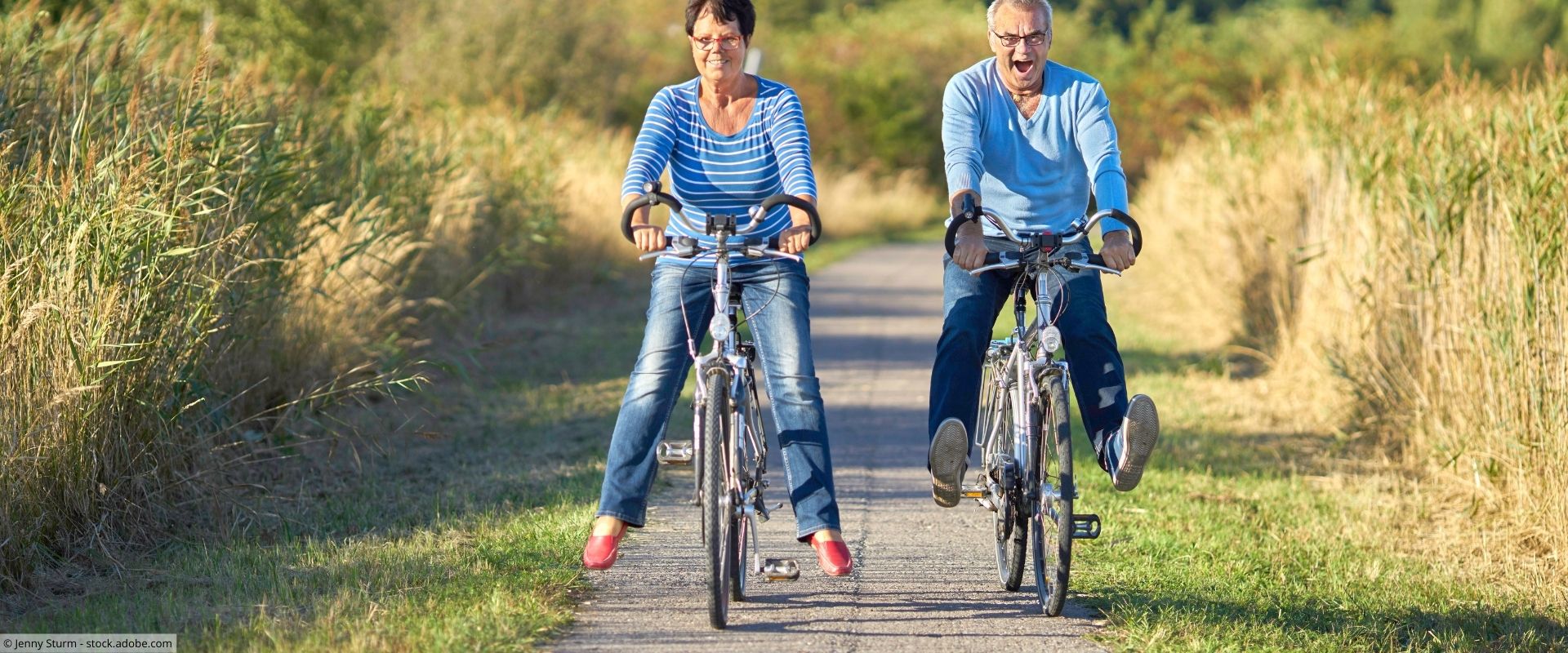 Bewegung tut gut Eine ältere Frau und ein älterer Mann fahren Fahrrad auf einem Feldweg